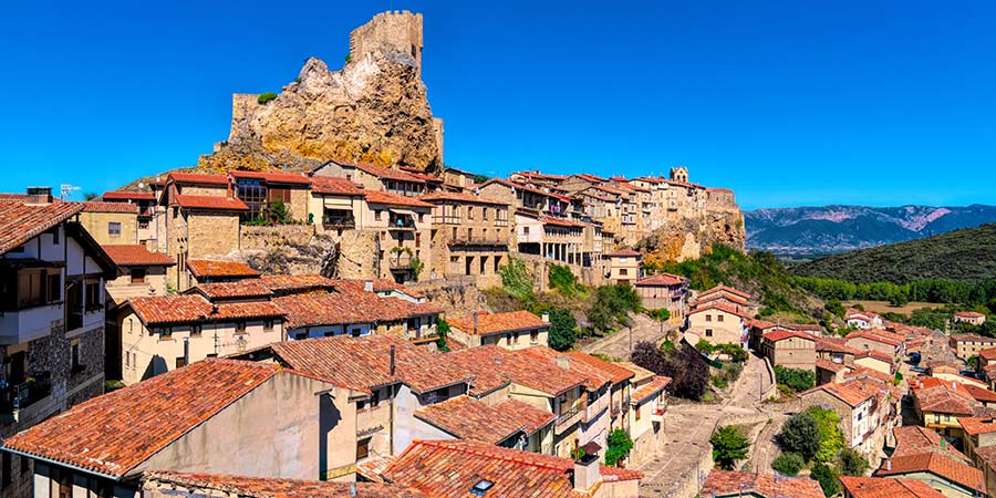 The medieval town of Frías, the castle sits on top of the hill, towering above the orange roof buildings below.