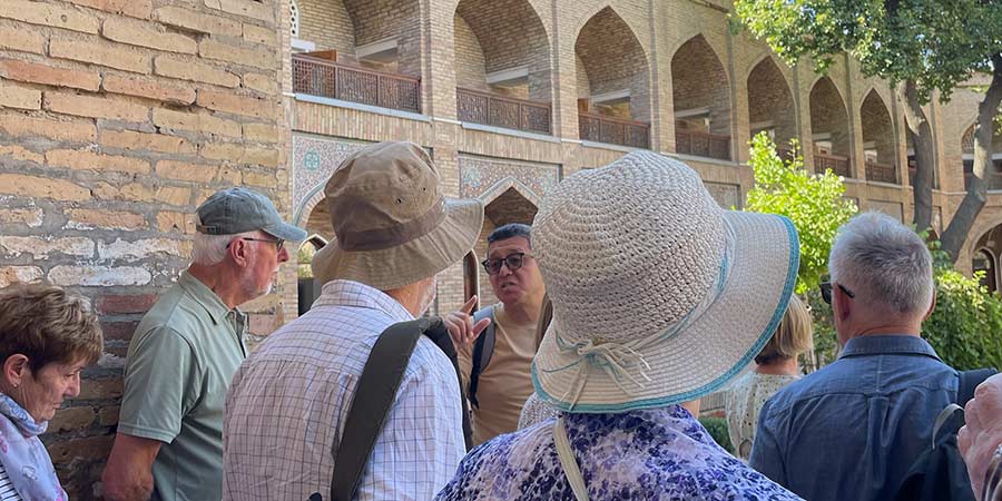 A Great Rail Journeys tour group enjoy a guided tour and admire the ornate architecture of Uzbeki buildings.